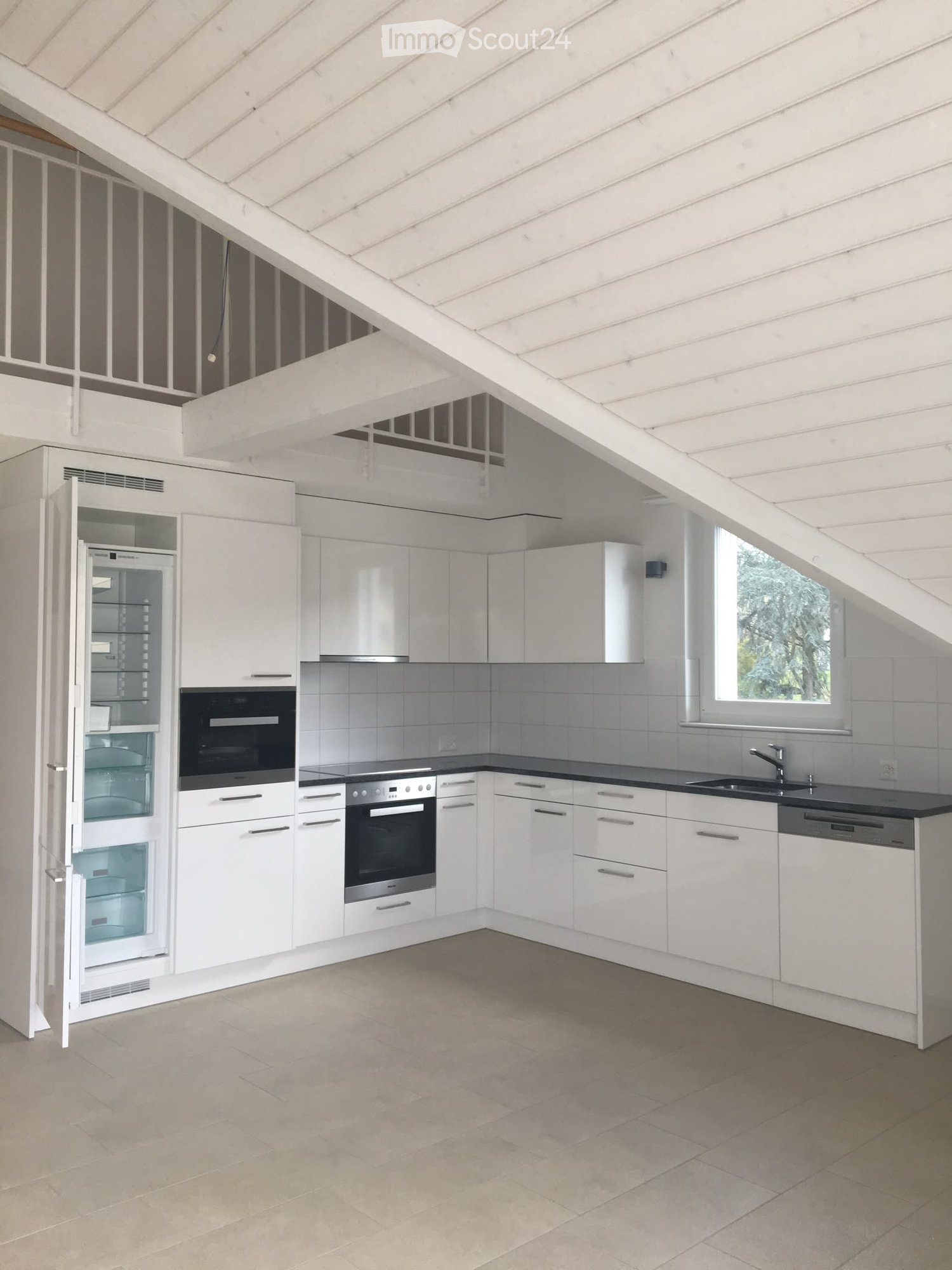 Modern kitchen with white cabinets, stainless steel appliances, and a black countertop. Features include a refrigerator, oven, dishwasher, and sink.