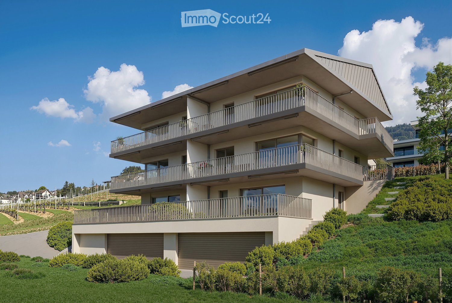 Modern two-story house with multiple balconies, situated on a hillside with well-maintained landscaping and a clear blue sky in the background.