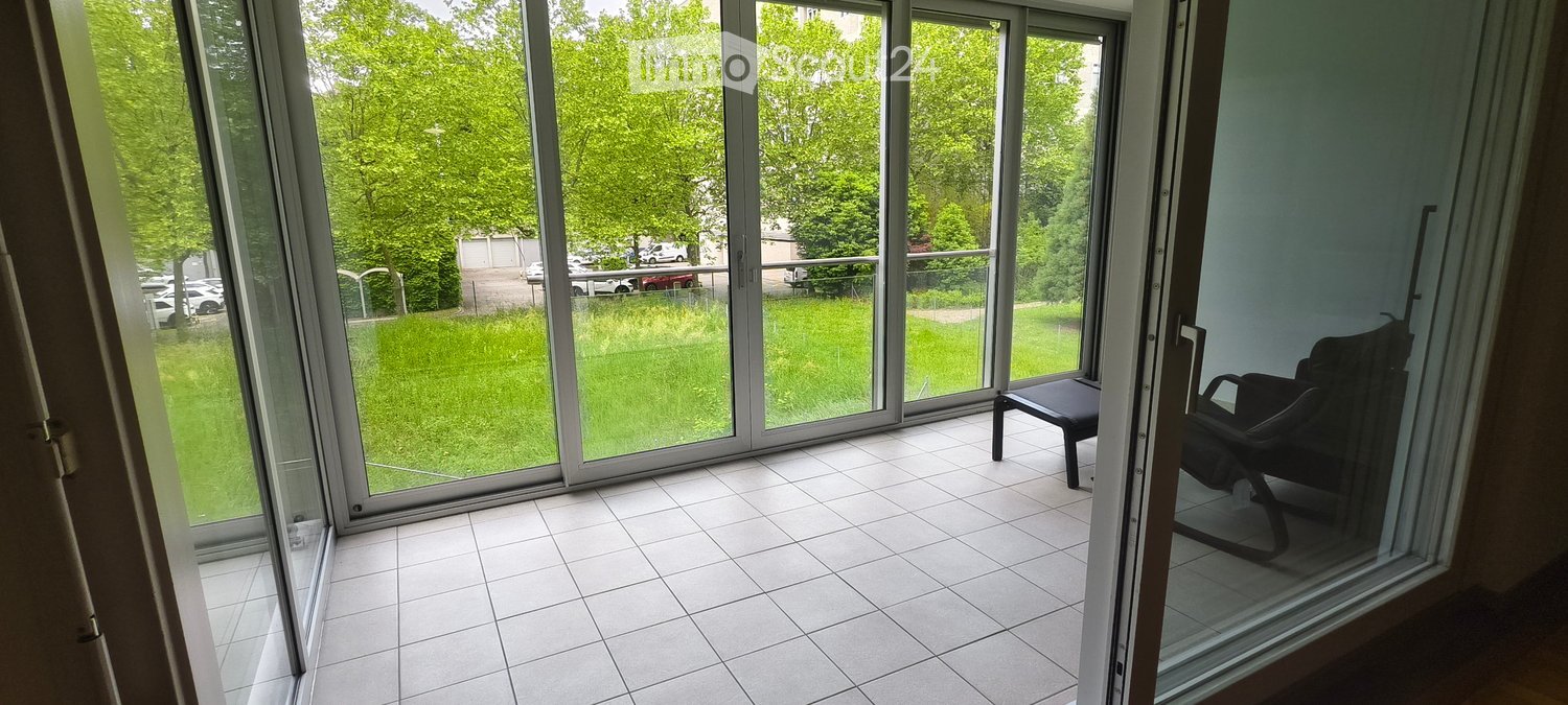 Balcony with tiled floor, large glass sliding doors, and a single black chair.