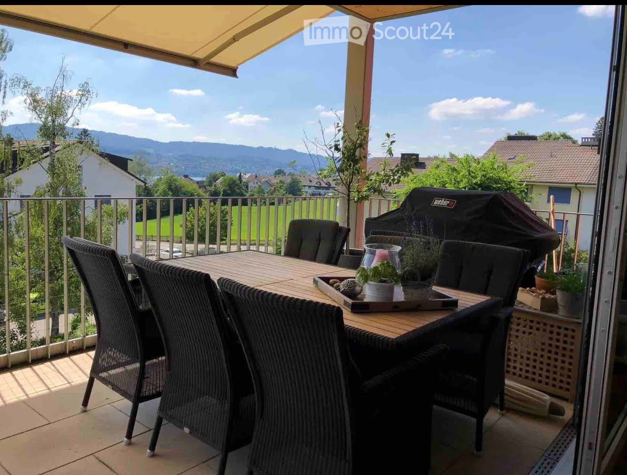Balcony with outdoor dining set, grill, potted plants, and scenic mountain view.