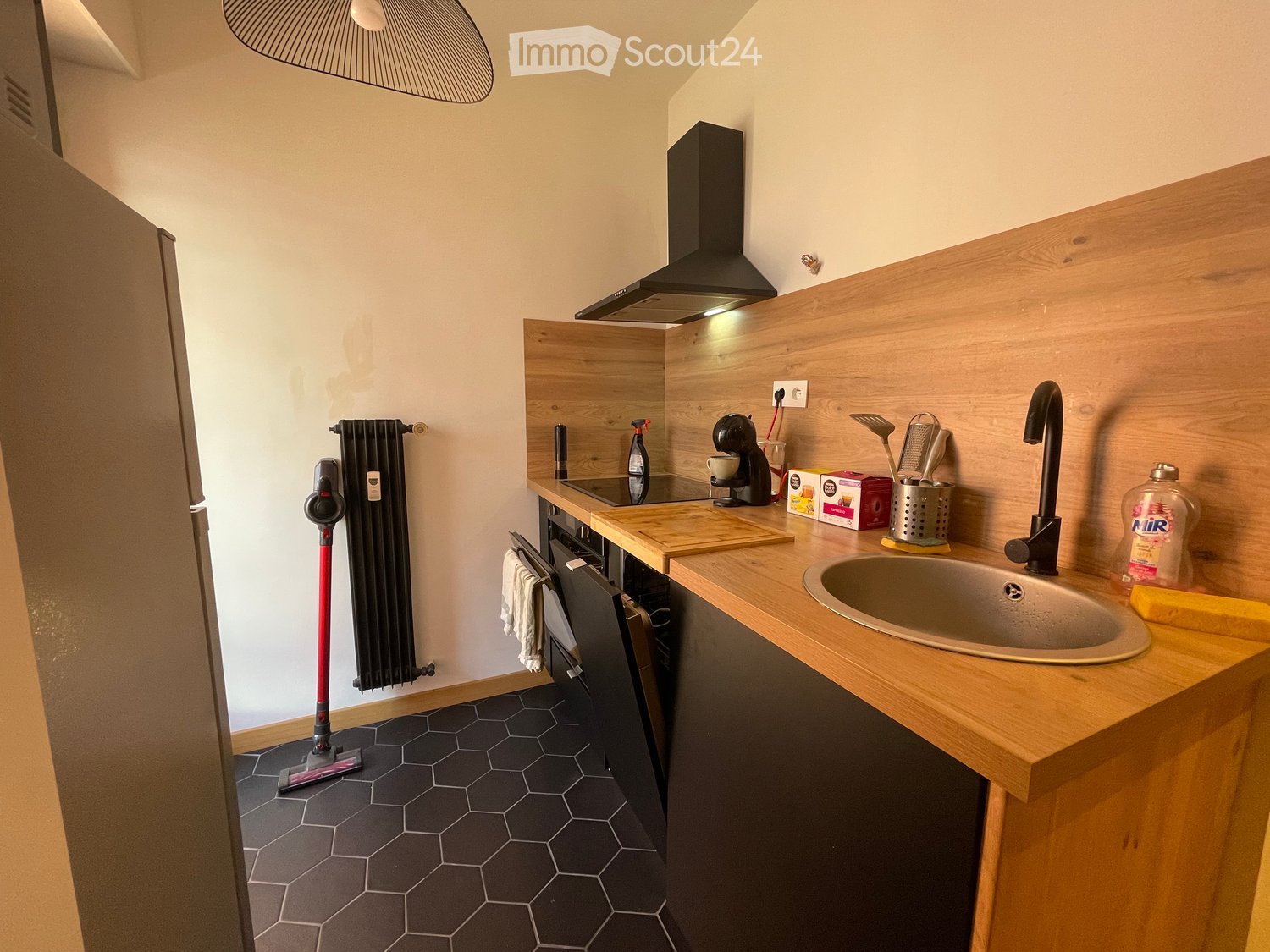 Modern kitchen with wooden countertops, stainless steel sink, black faucet, coffee maker, and various kitchen items on the counter.