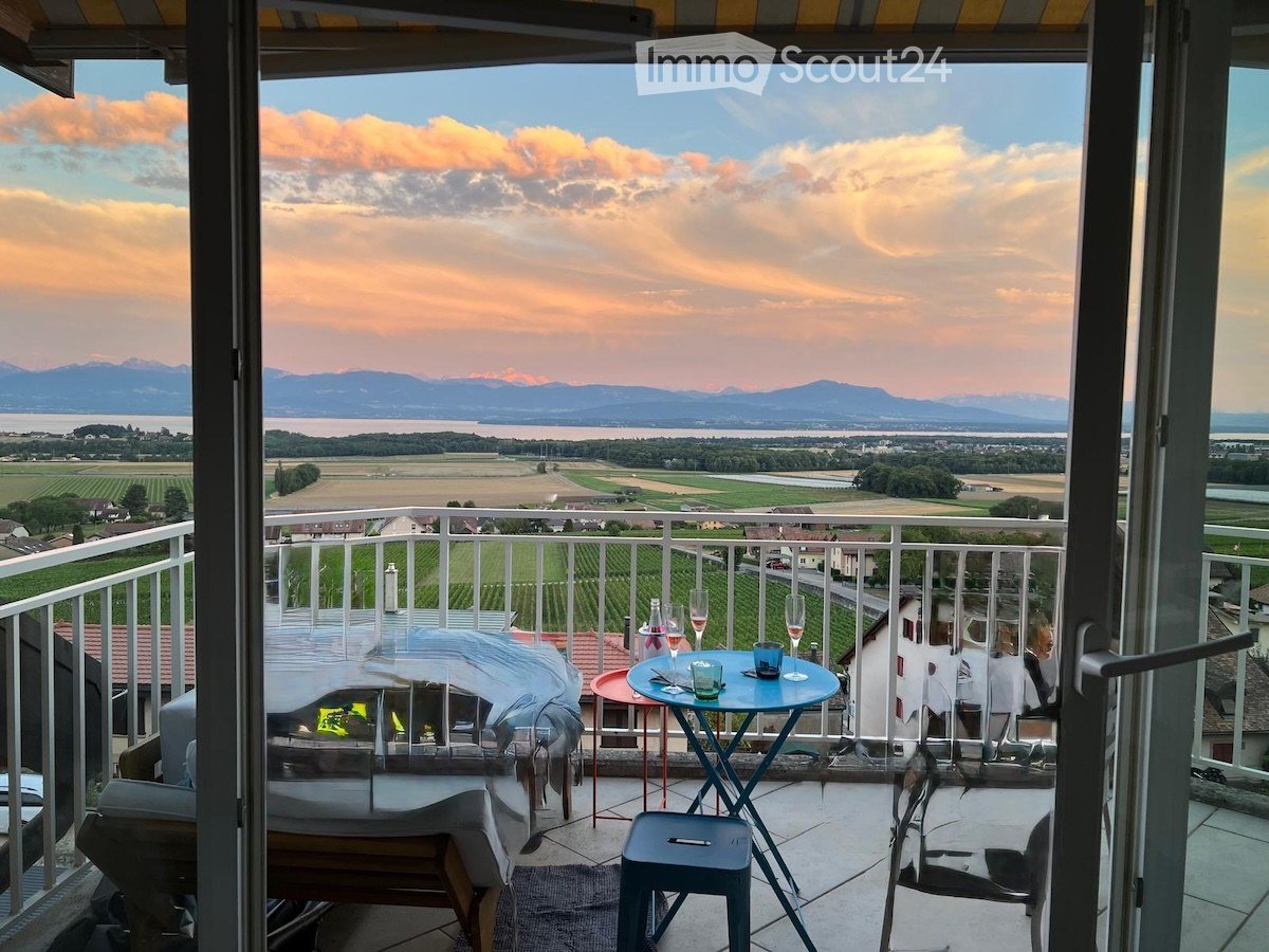 Balcony with scenic view of mountains and countryside, furnished with a small table, chairs, and a stool.
