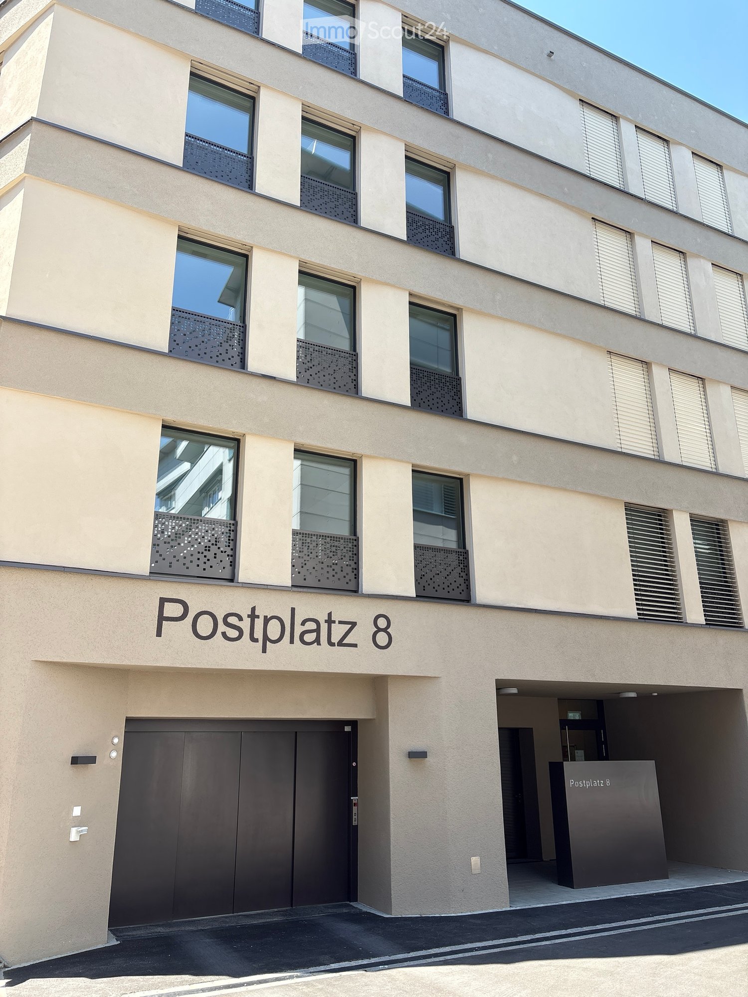 Modern multi-story building with large windows, decorative metal balustrades, and a prominent entrance labeled "Postplatz 8".