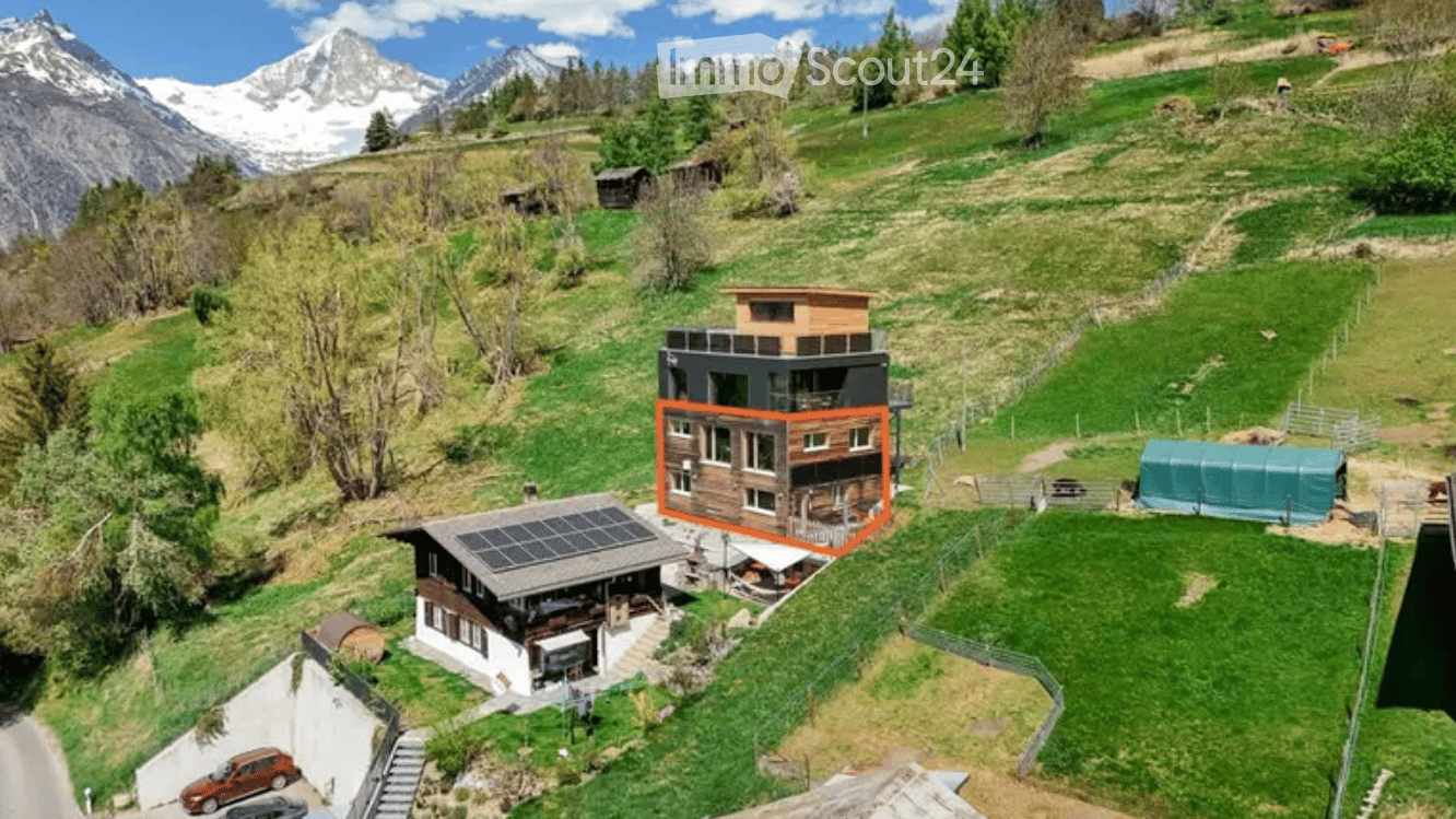 House with solar panels, wooden exterior, surrounded by green grass and mountains