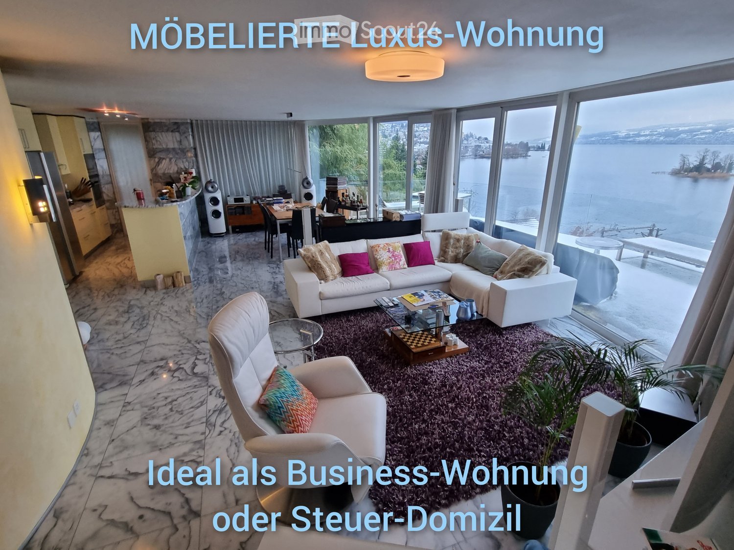 Luxurious living room with a white sectional sofa, armchair, coffee table, dining area, and large windows overlooking a scenic view.