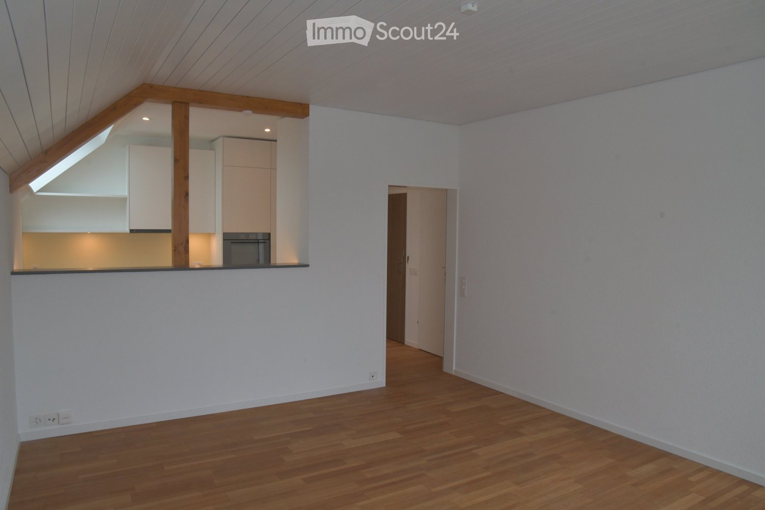 empty room, wooden floor, white walls, kitchen area, wooden beams