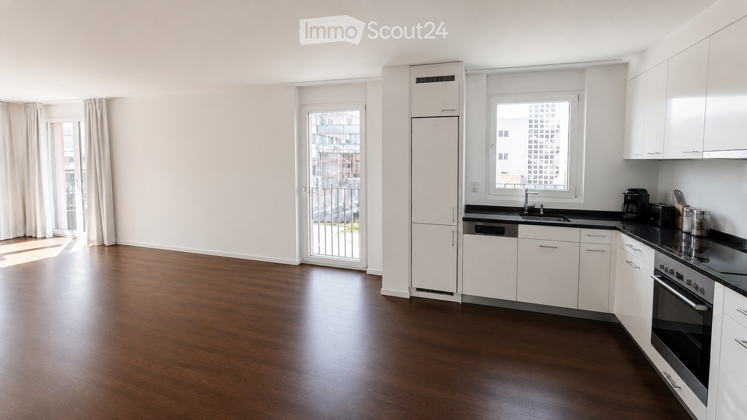 Modern kitchen with white cabinets, black countertops, stainless steel appliances, and wooden flooring.