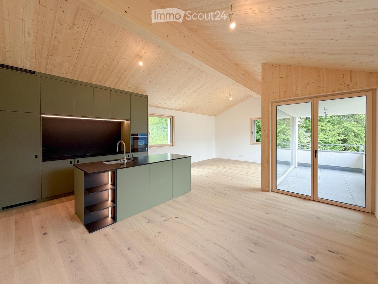 Modern kitchen with light green cabinets, wooden ceiling, and large sliding glass doors leading to a balcony.
