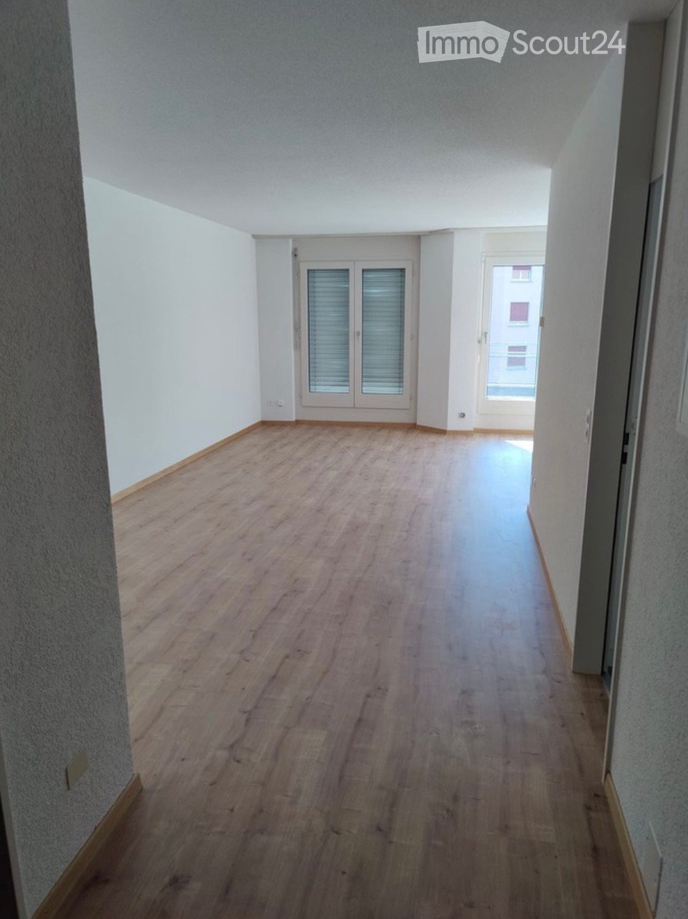 Empty hallway with wooden flooring, white walls, and two doors leading to other rooms.