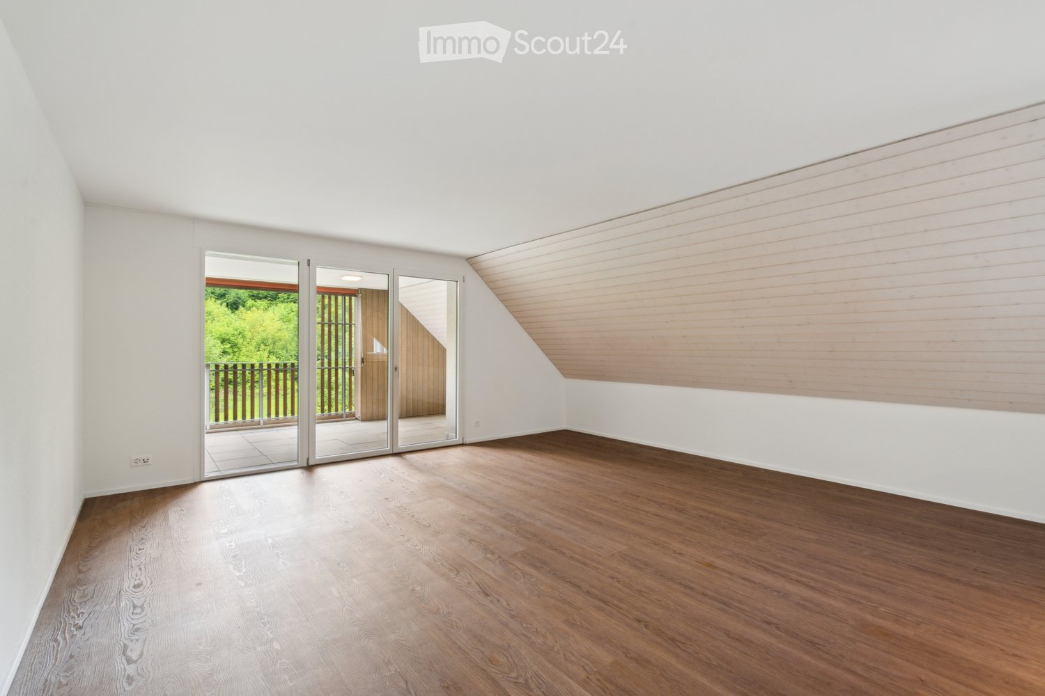 Empty room with wooden flooring, white walls, and large sliding glass doors leading to an outdoor area.