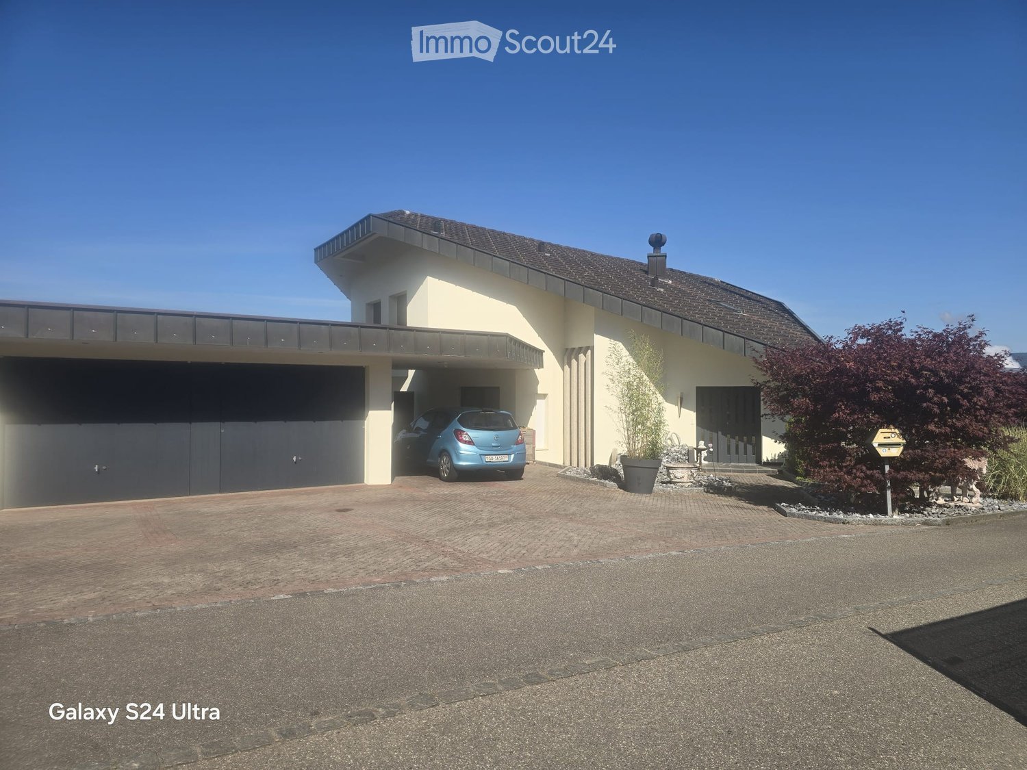 Modern two-story house with a garage, a balcony, and a well-maintained garden area.