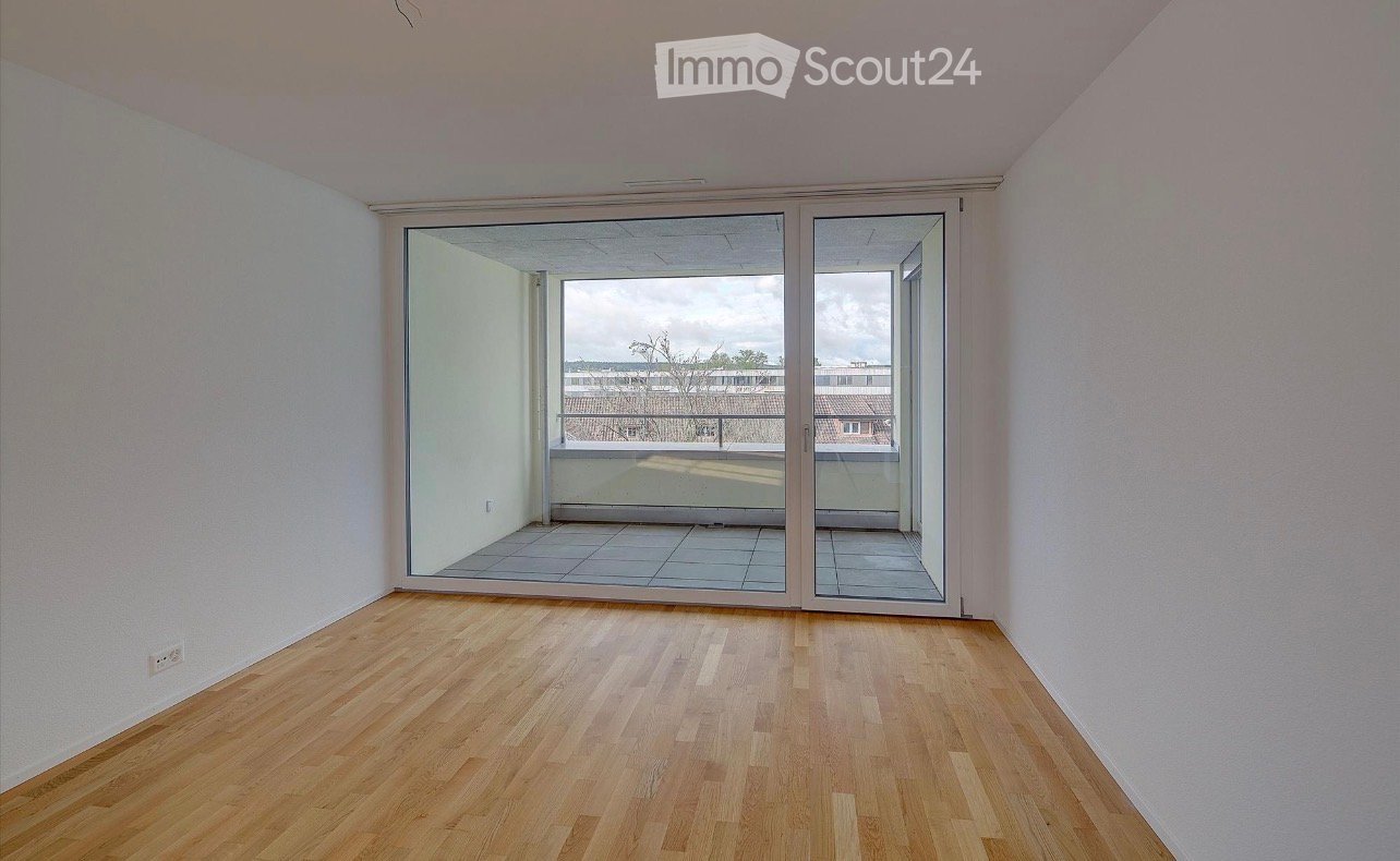 Empty room with wooden flooring, white walls, and large sliding glass doors leading to a balcony.