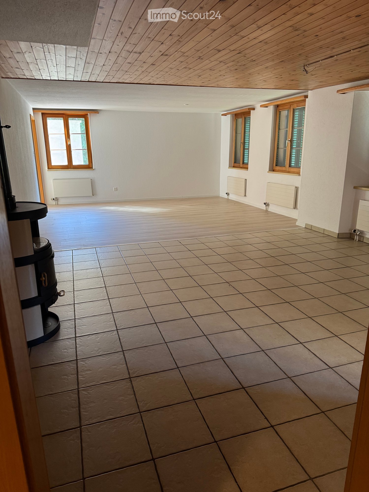 Empty room with wooden ceiling, tiled floor, and wooden-framed windows. No furniture or equipment present.