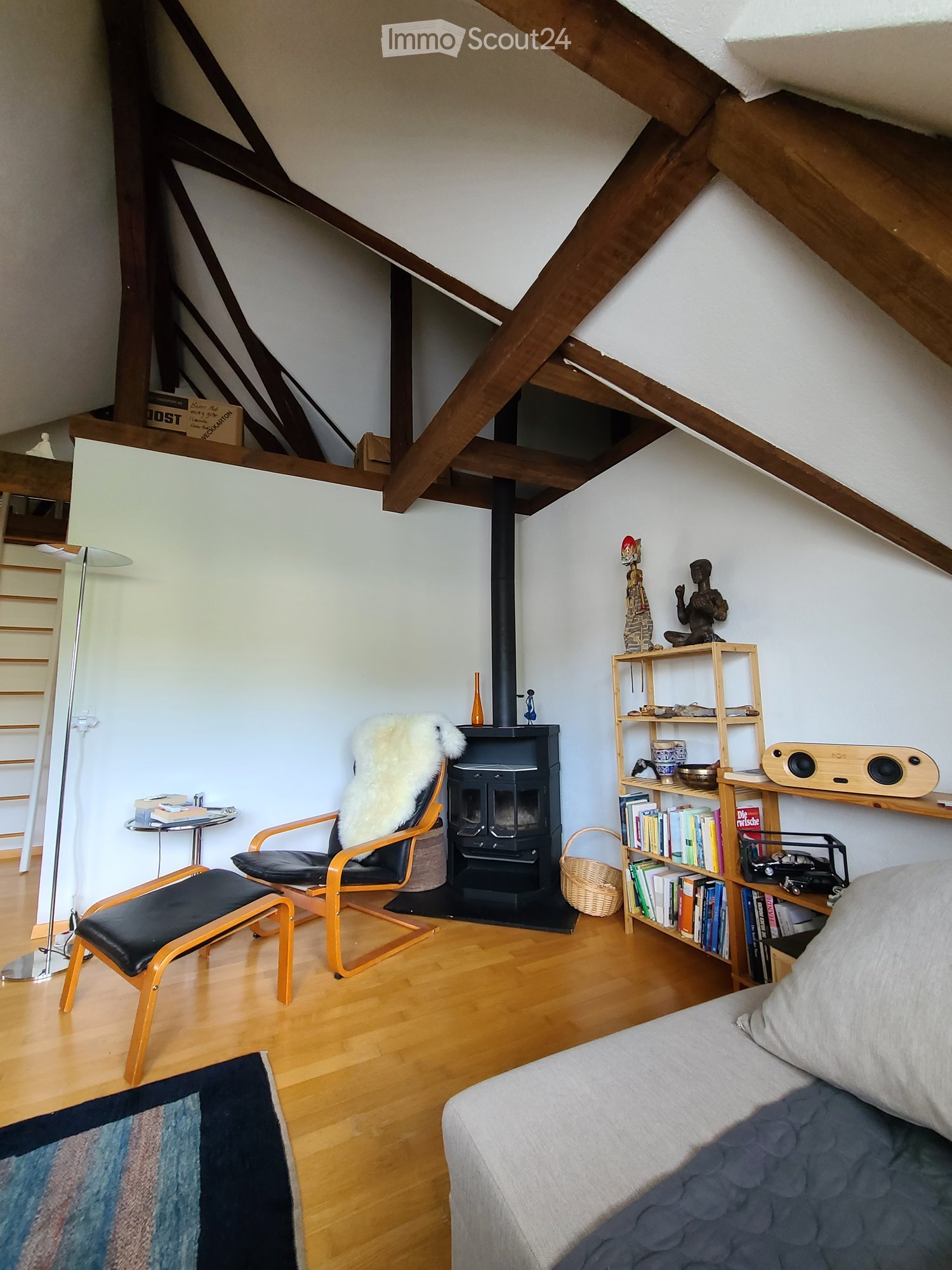 Living room with wooden floor, fireplace, sofa, chair, bookshelf, and floor lamp.
