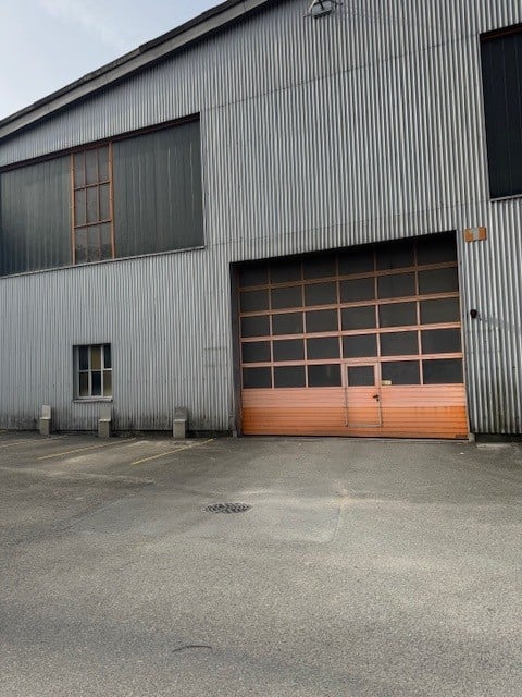 Industrial building with metal siding, large double garage door, windows, parking area