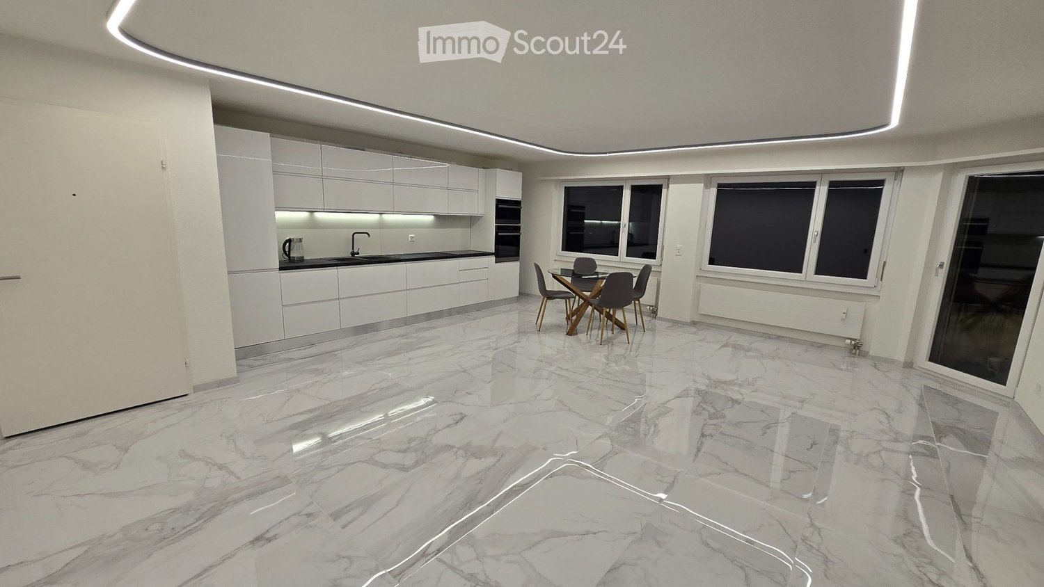 Modern kitchen and dining area with white cabinets, marble flooring, and large windows. Includes a sink, faucet, oven, and a dining table with chairs.
