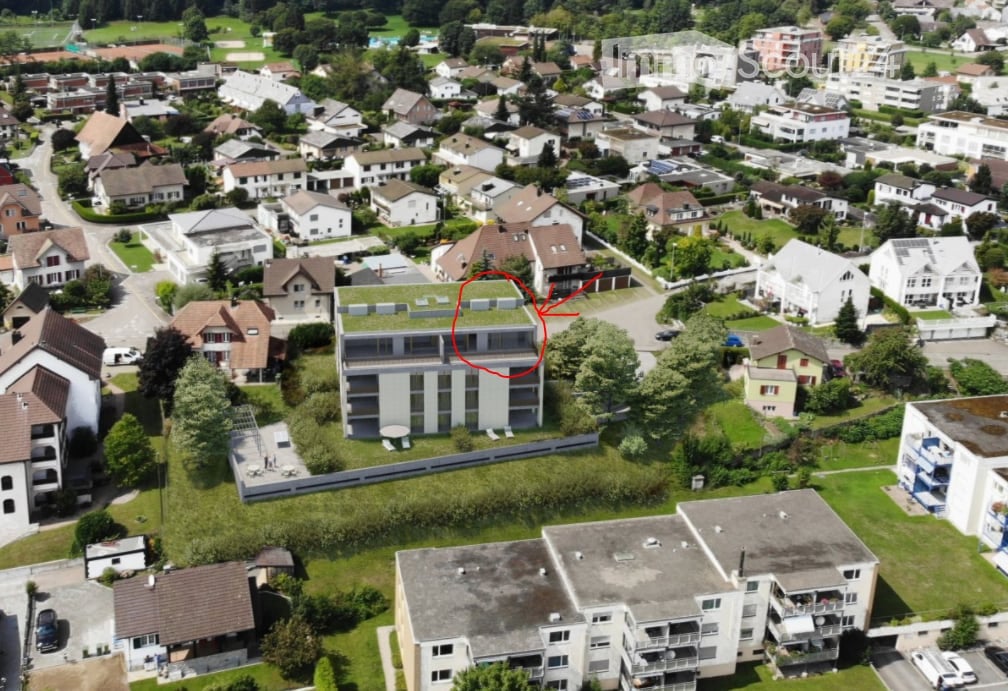 Aerial view of a residential area with multiple houses, green spaces, and a highlighted building with a green roof.