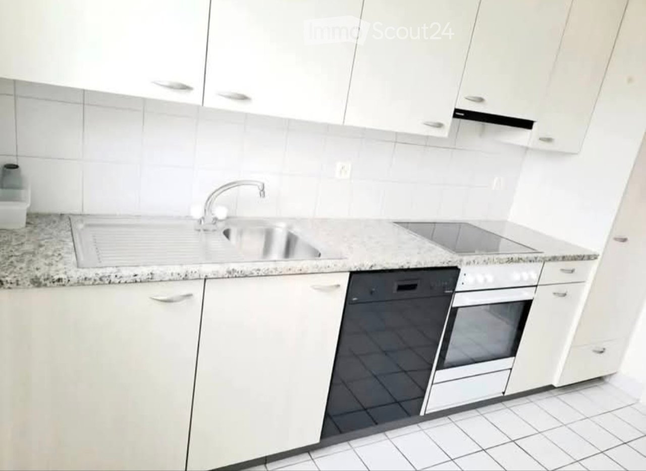 Modern kitchen with white cabinets, granite countertop, stainless steel sink, and built-in oven and dishwasher.