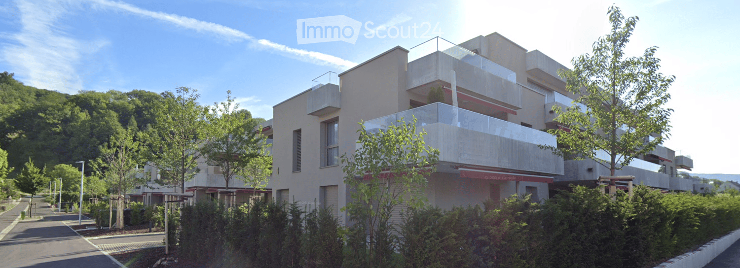 Modern multi-story residential building with balconies and contemporary design, surrounded by greenery and trees.