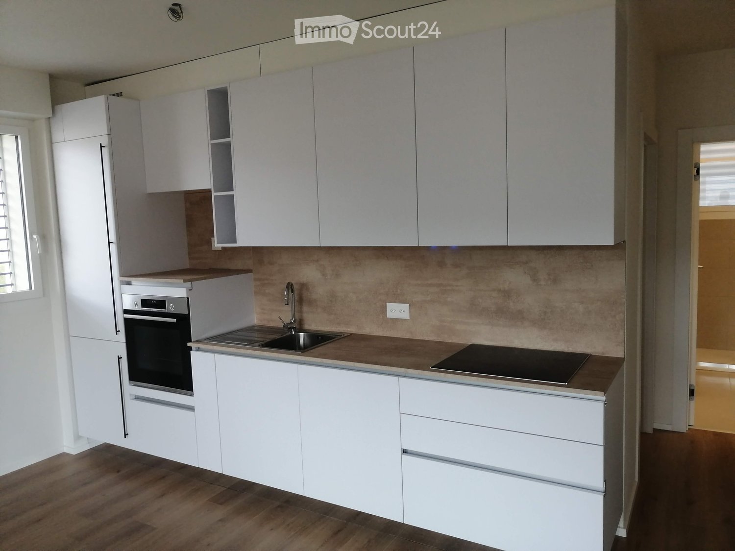 Modern kitchen with white cabinets, stainless steel appliances, and a wooden countertop.