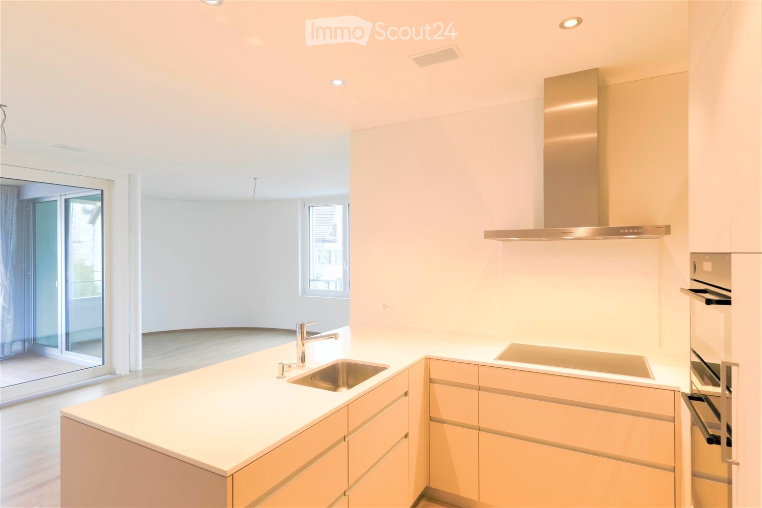 Modern kitchen with light-colored cabinets, a central island, and a stainless steel sink and oven.