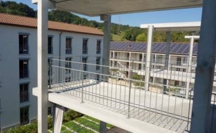 Balcony overlooking a modern residential complex with multiple buildings and a landscaped garden area below.