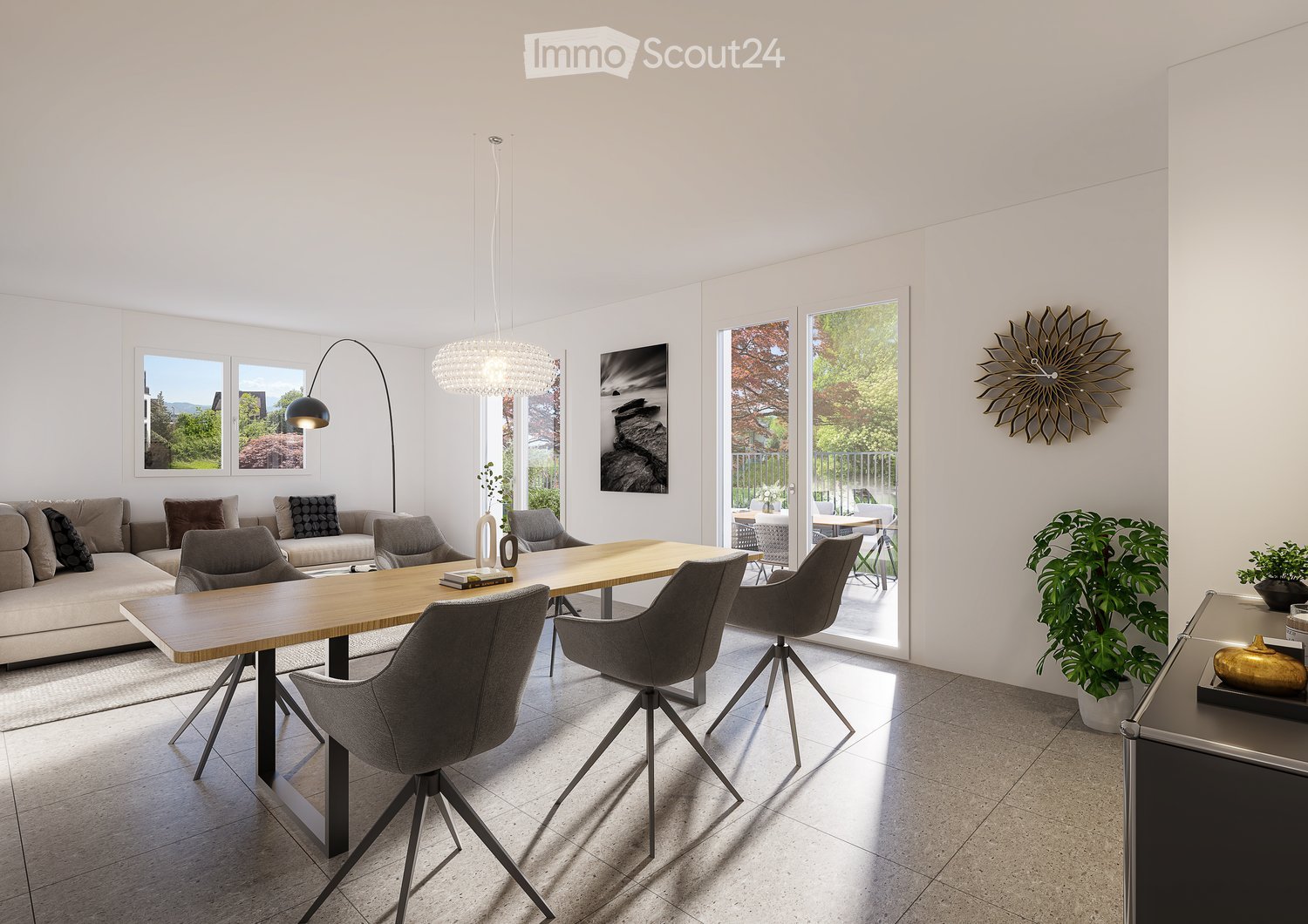 Modern living room with a large wooden dining table, grey chairs, a beige sofa, floor lamp, wall clock, and plants. Large windows and sliding glass doors lead to a balcony.