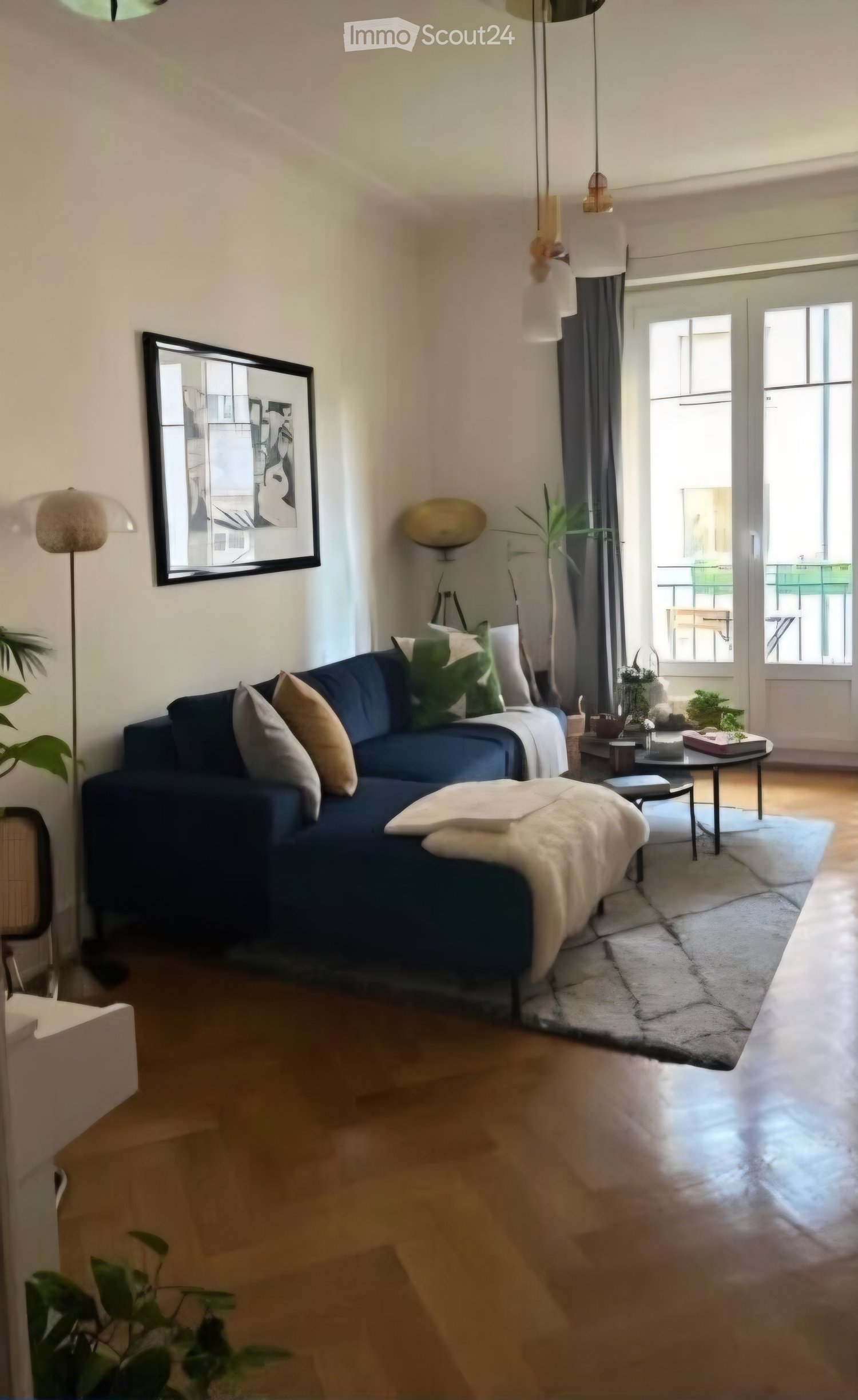 Modern living room with a dark blue sectional sofa, wooden coffee table, ottoman, floor lamp, and large windows with a view.