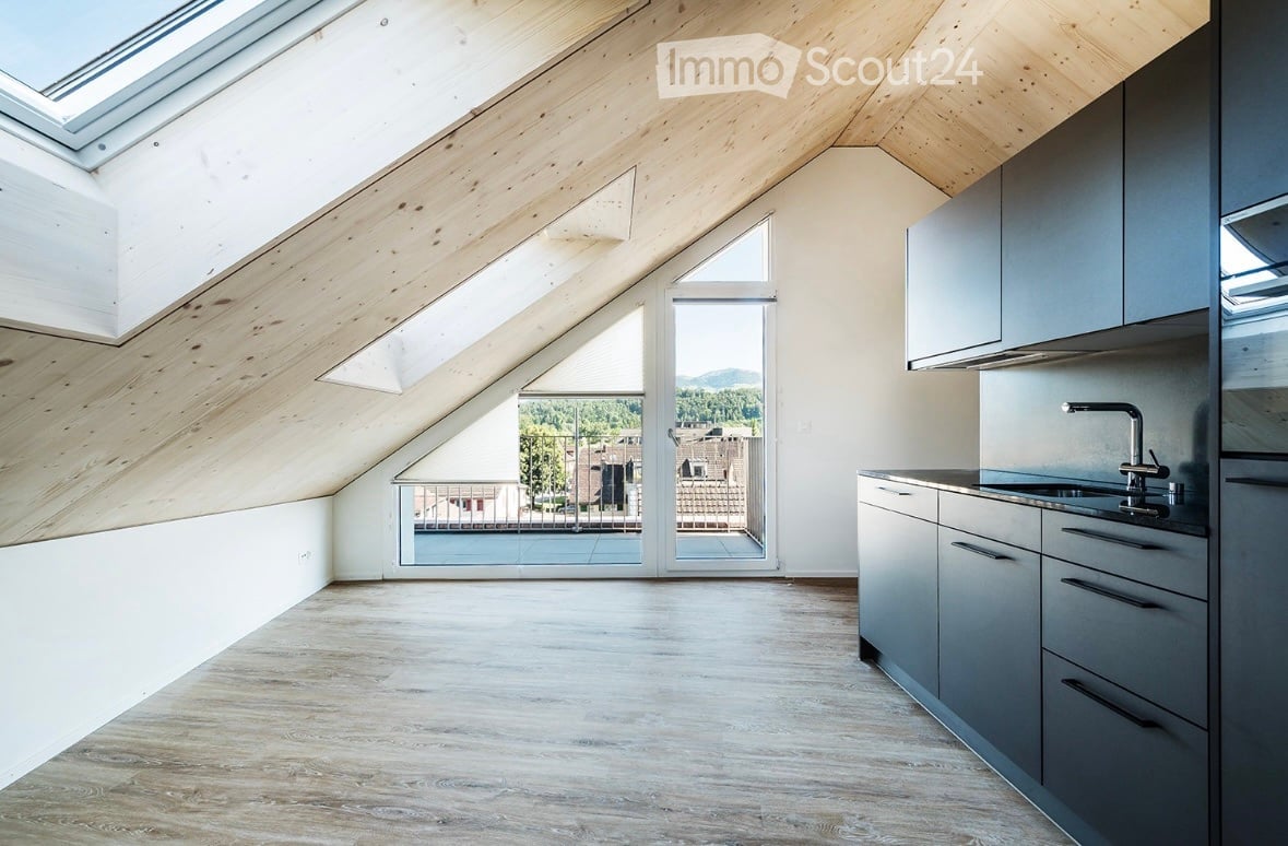 Modern kitchen with grey cabinets, wooden flooring, and a large window offering a scenic view.