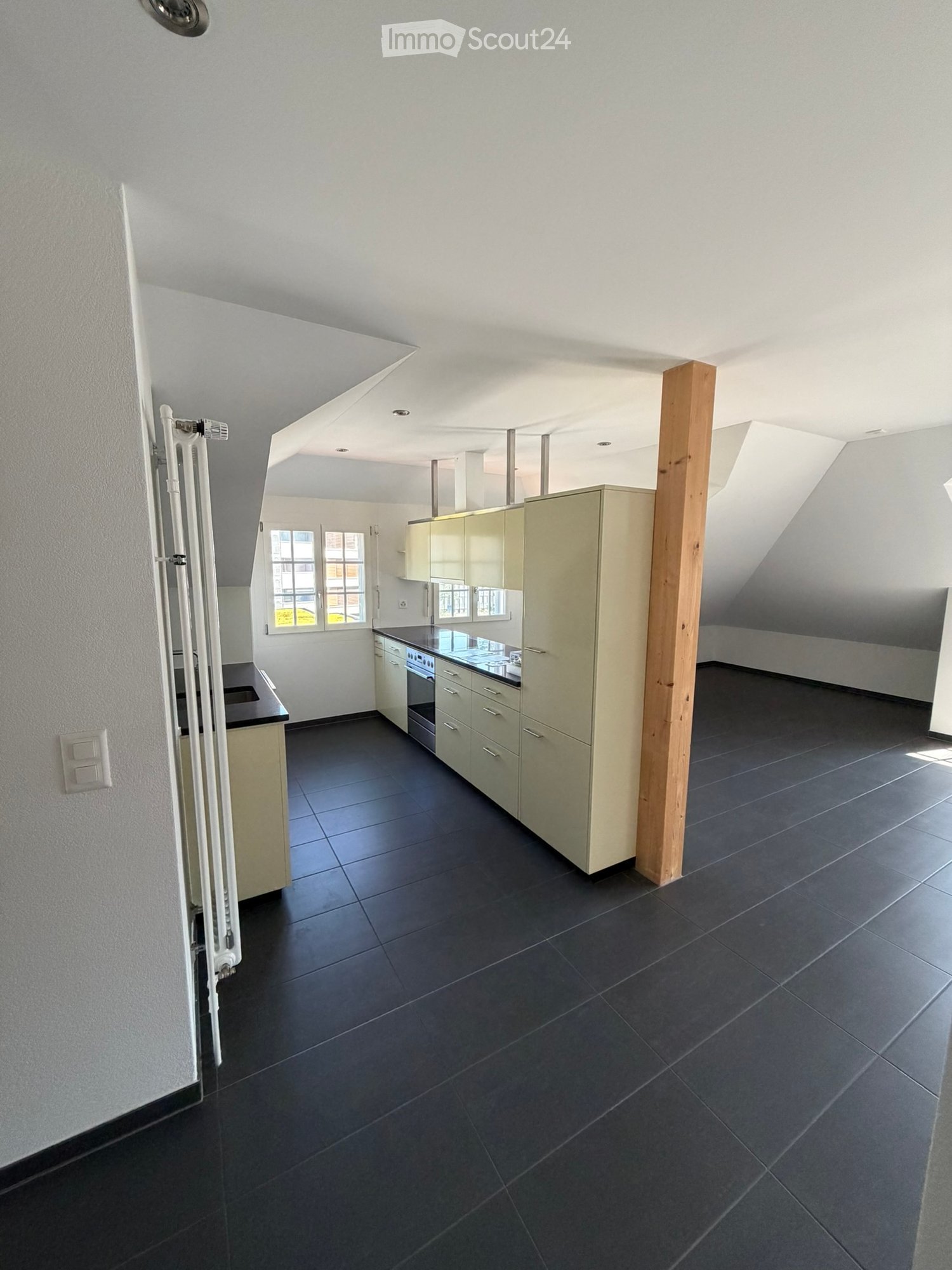 Modern kitchen with dark tiled floor, light-colored cabinets, and built-in oven. Features large windows and a sleek design.