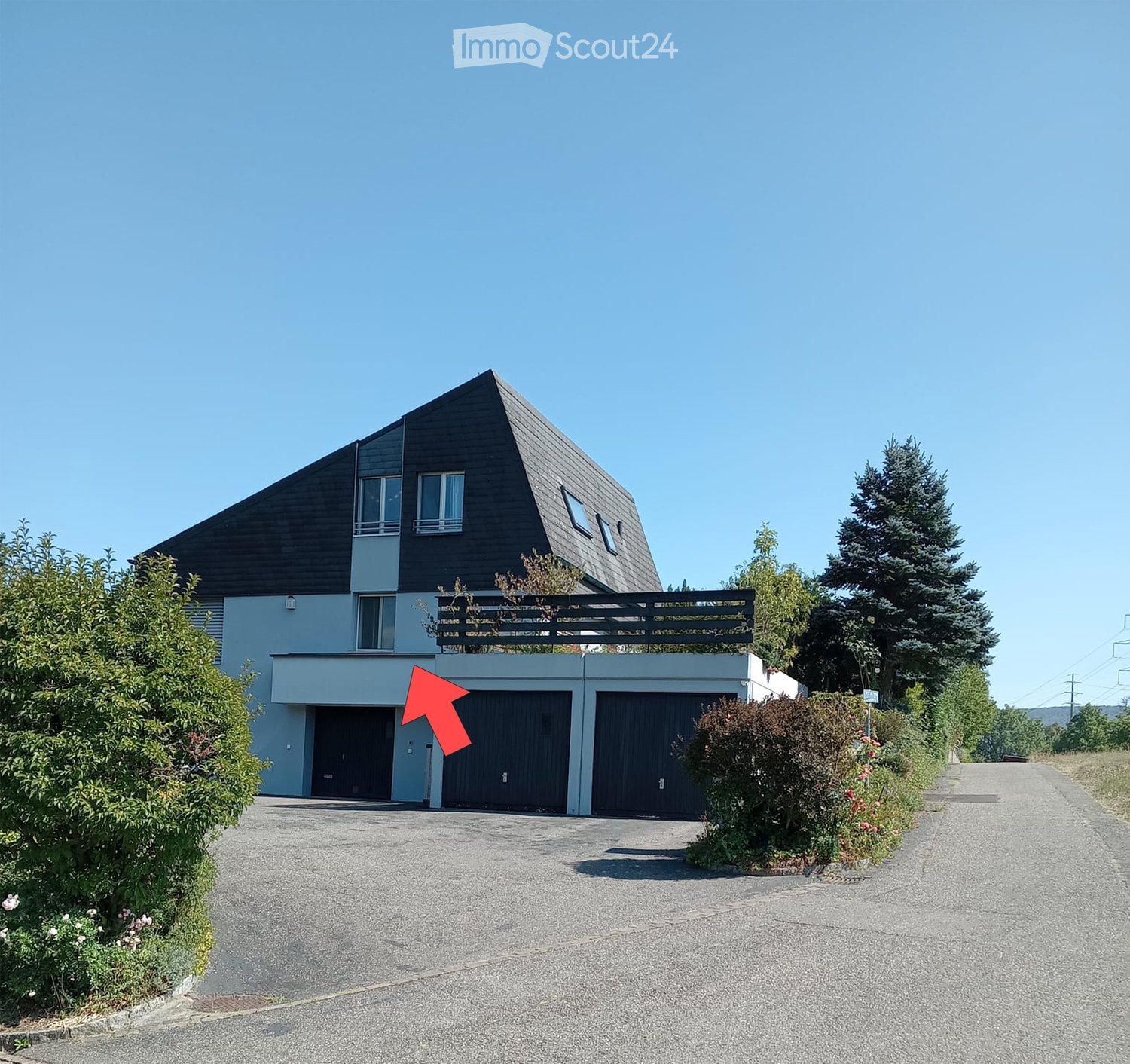 Modern two-story house with a dark roof, large windows, and a spacious driveway leading to a double garage.
