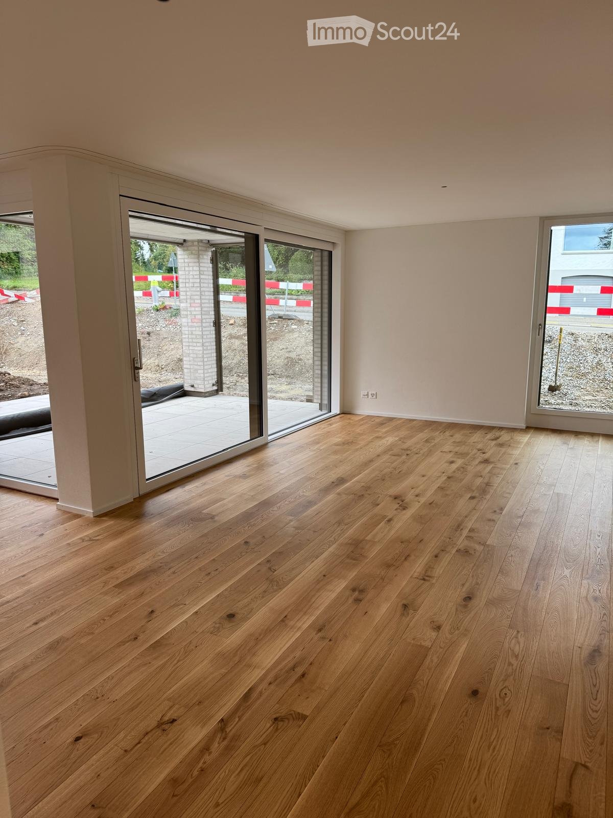 Empty room with light wooden flooring and large sliding glass doors leading to an outdoor area.