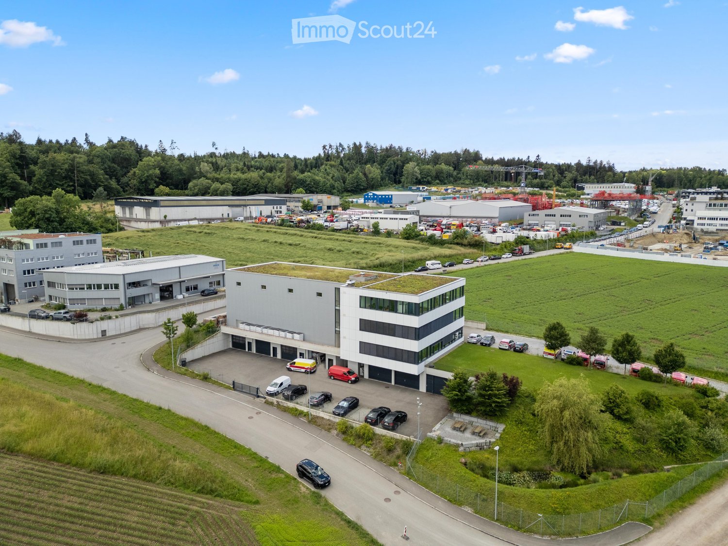 Aerial view of a modern industrial complex with multiple buildings, parking lots, and green spaces.
