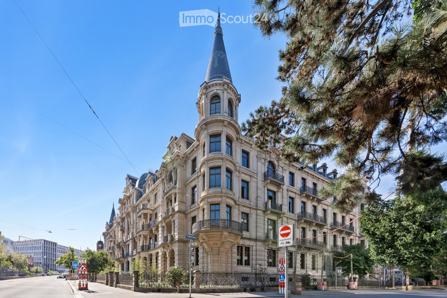 Ornate multi-story building with a distinctive tower and spire, featuring large windows, balconies, and intricate architectural details.