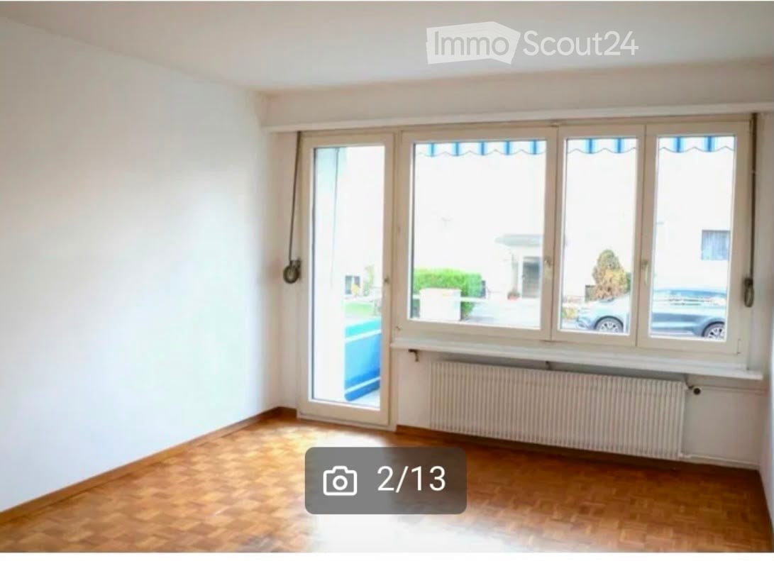 Empty room with wooden flooring, white walls, large windows, and a radiator. No furniture or equipment present.