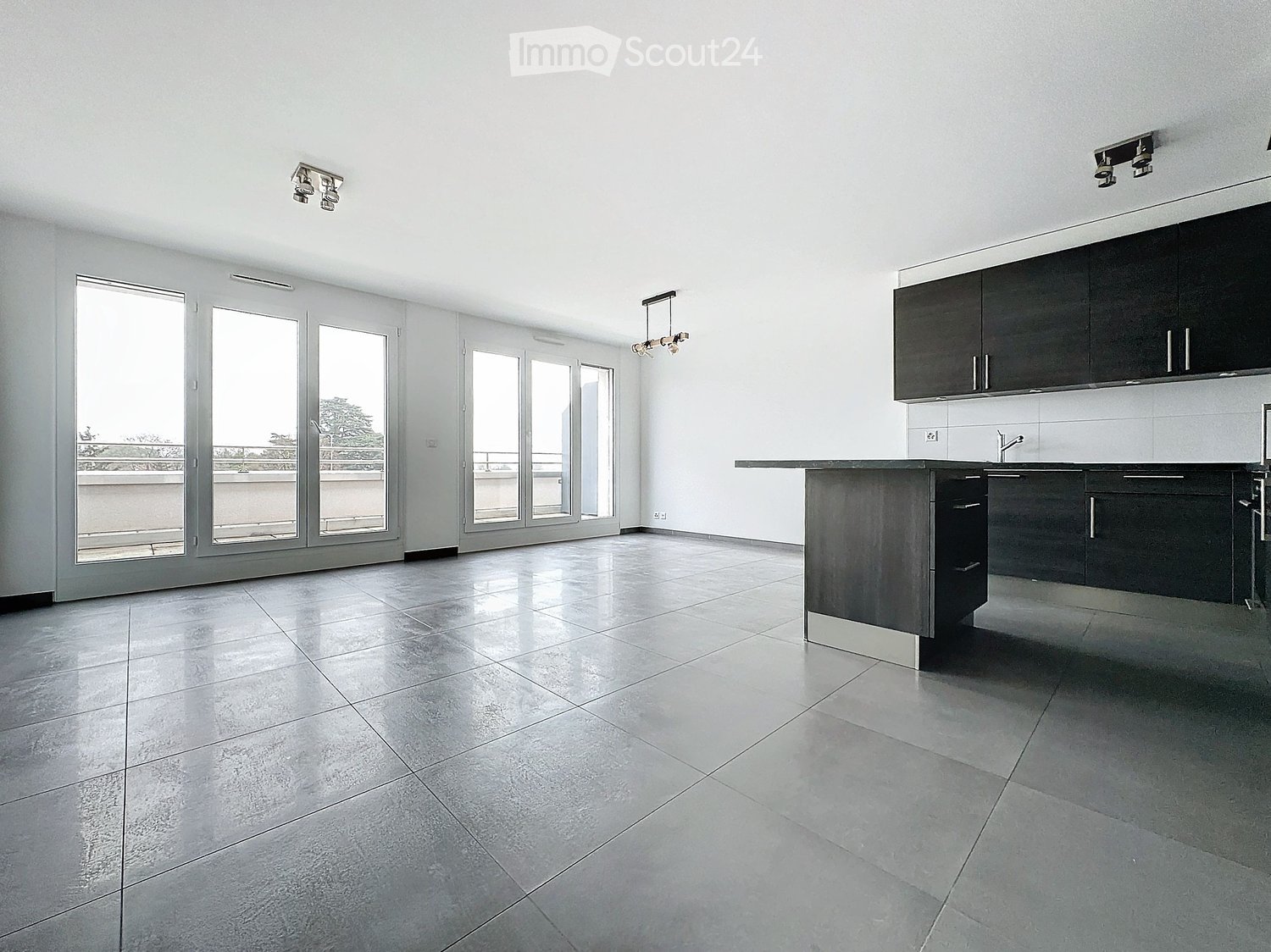 Modern kitchen with dark cabinets, a central island, and large windows leading to a balcony.