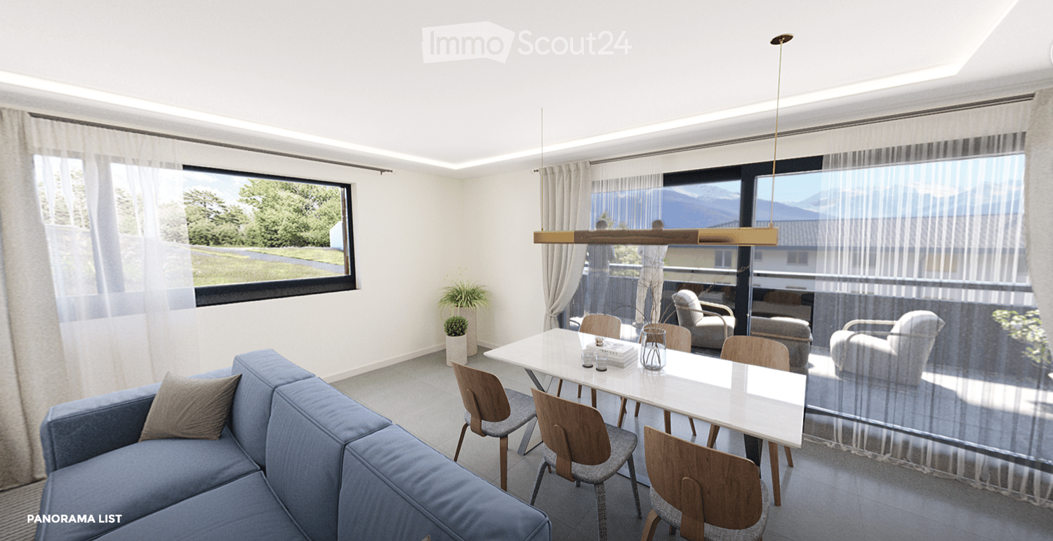 Modern living and dining area with a blue sofa, white dining table, wooden chairs, pendant light, and large windows with a scenic view.