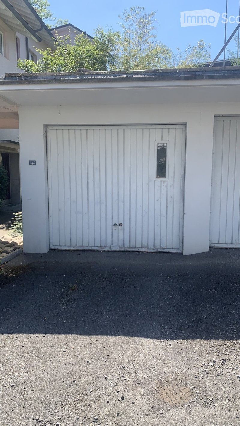 White garage with a single door and small window, situated on a gravel surface.