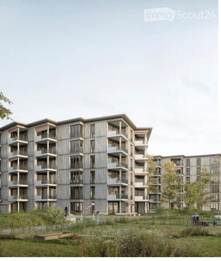 Modern multi-story residential building with balconies and large windows, surrounded by green space and trees.
