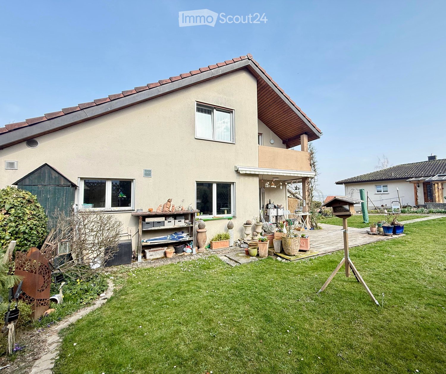 2 story house, beige exterior, brown roof, balcony, garden, patio, various potted plants