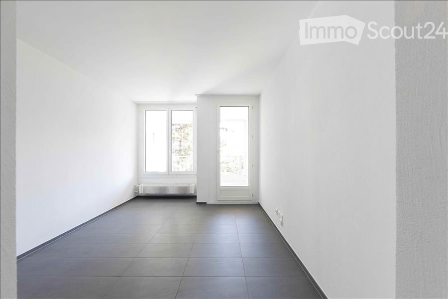 Completely empty room with white walls, tiled floor, and large windows. No furniture or equipment.