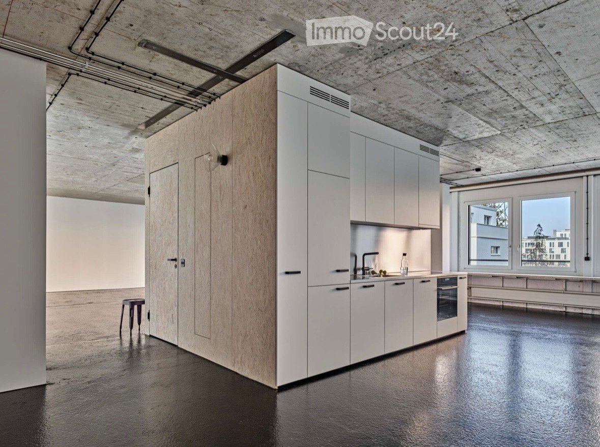 Modern kitchen with white cabinets, wooden paneling, stainless steel sink, and a sleek black floor.