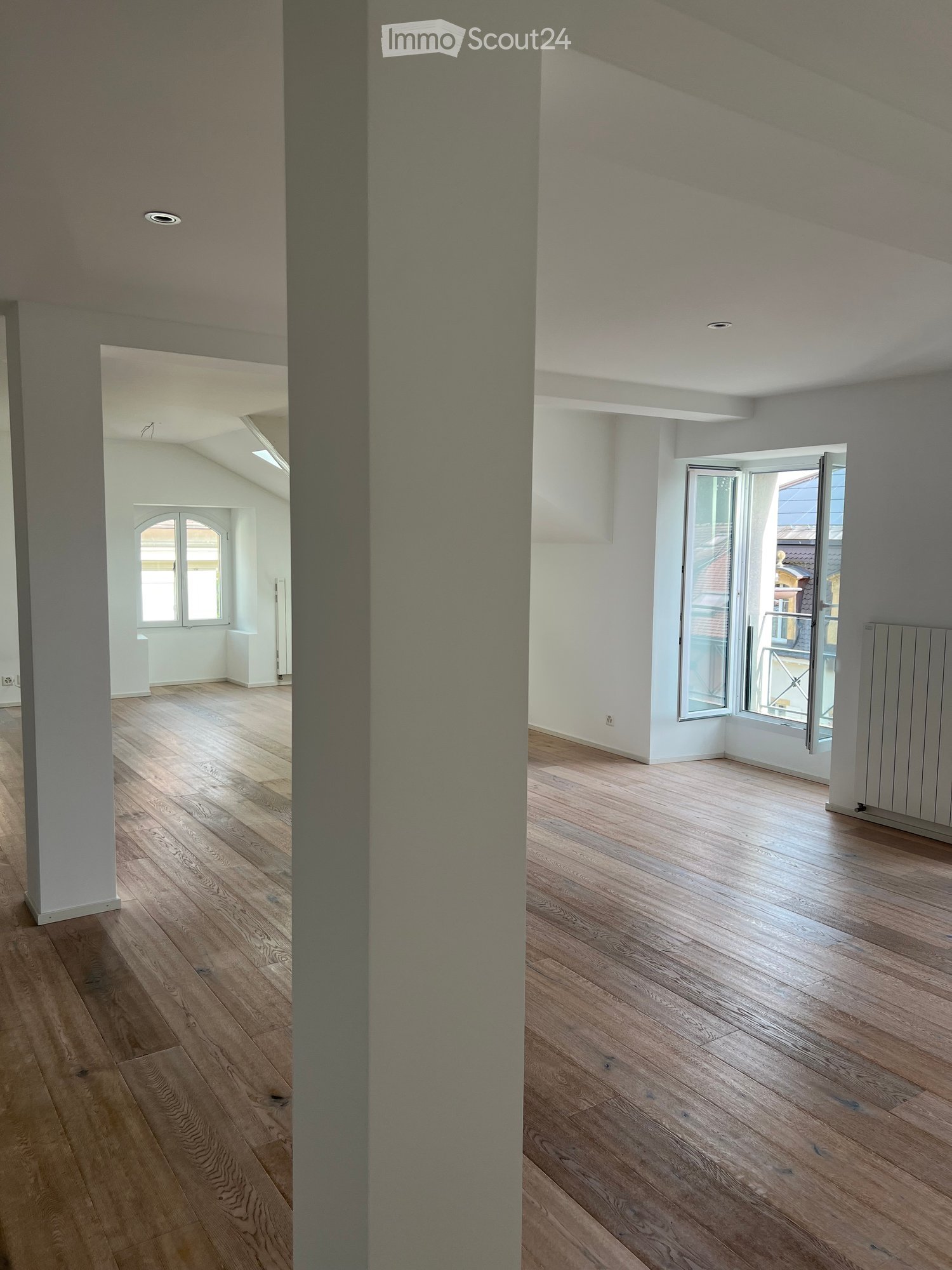 Empty room with wooden flooring, white walls, and large windows. No furniture or equipment present.