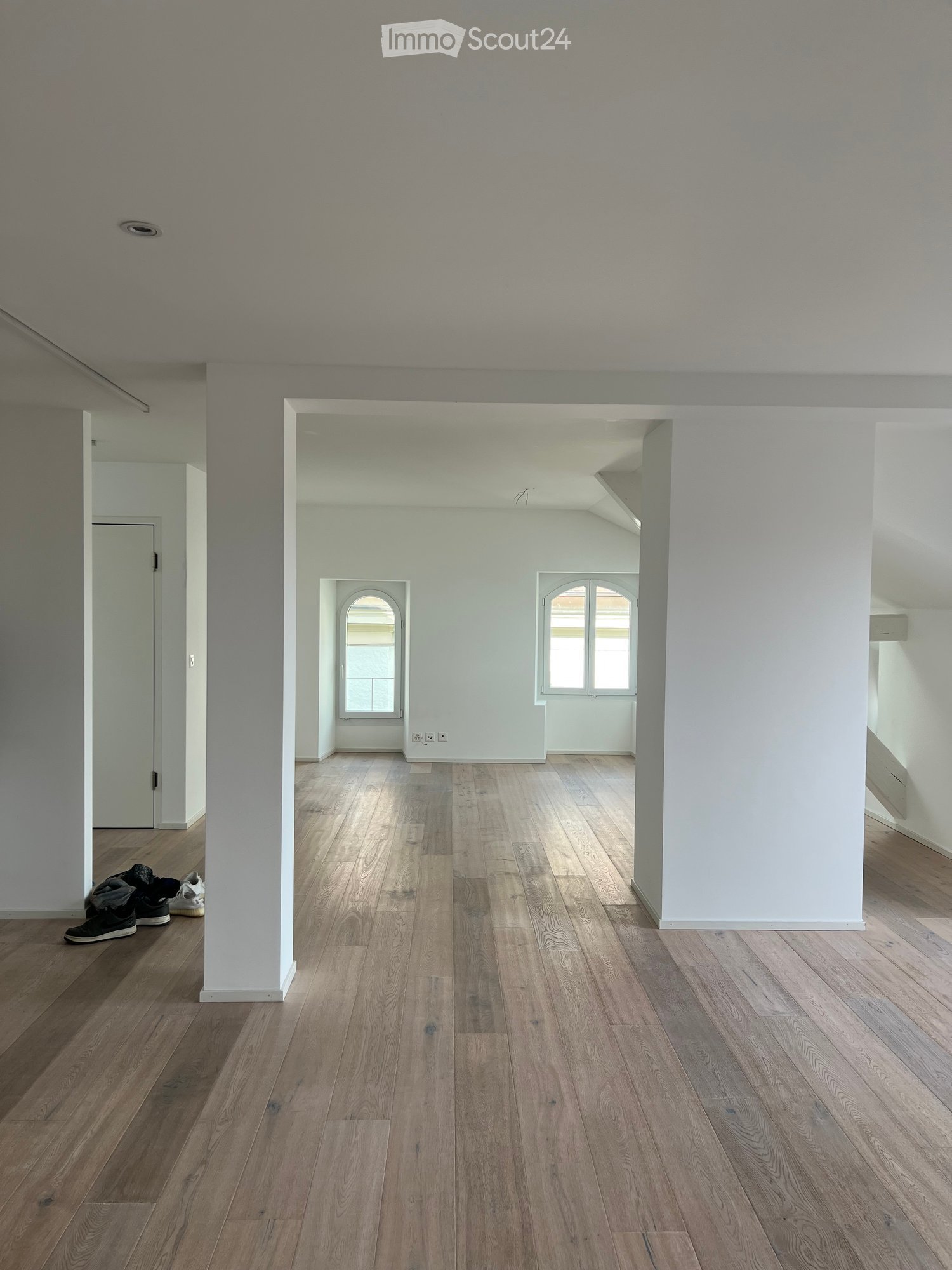 Empty room with wooden flooring, white walls, and large windows. No furniture or equipment present.