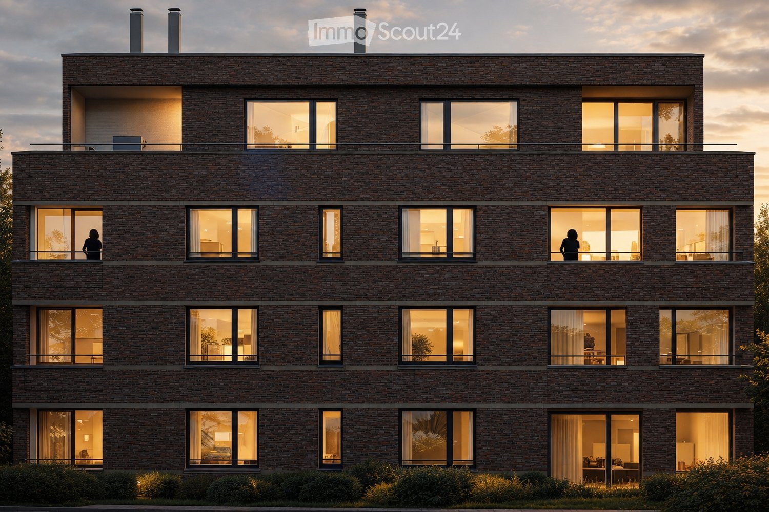 Modern three-story brick building with large windows and balconies, illuminated interiors visible through the glass.