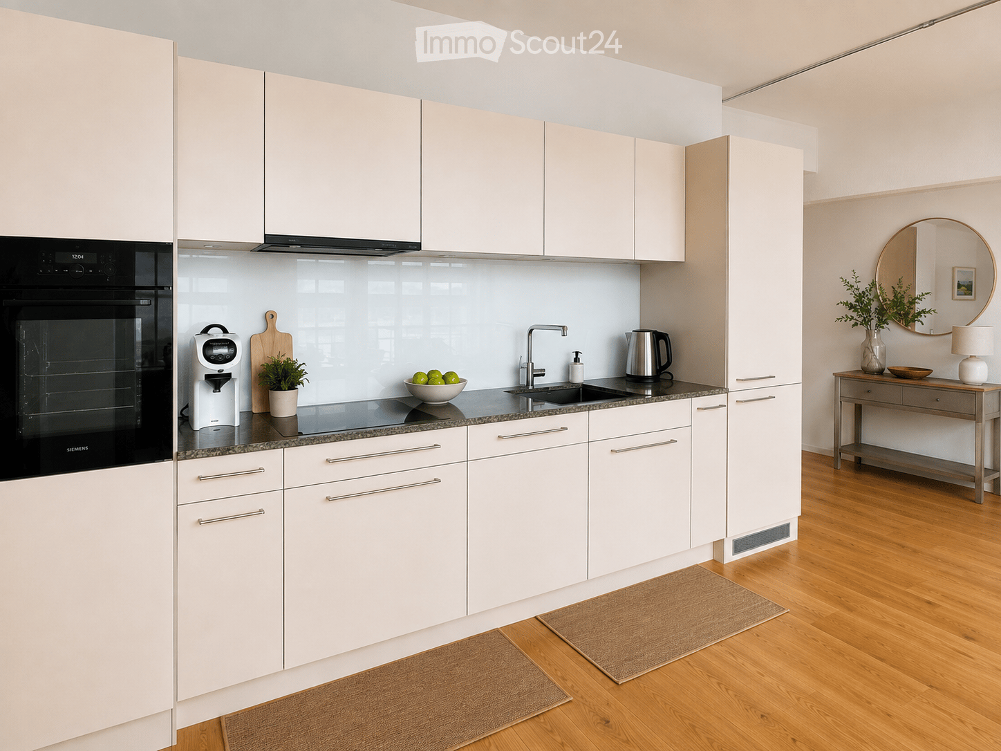 Modern kitchen with white cabinets, granite countertop, stainless steel appliances, and a small table with a lamp and plant in the corner.