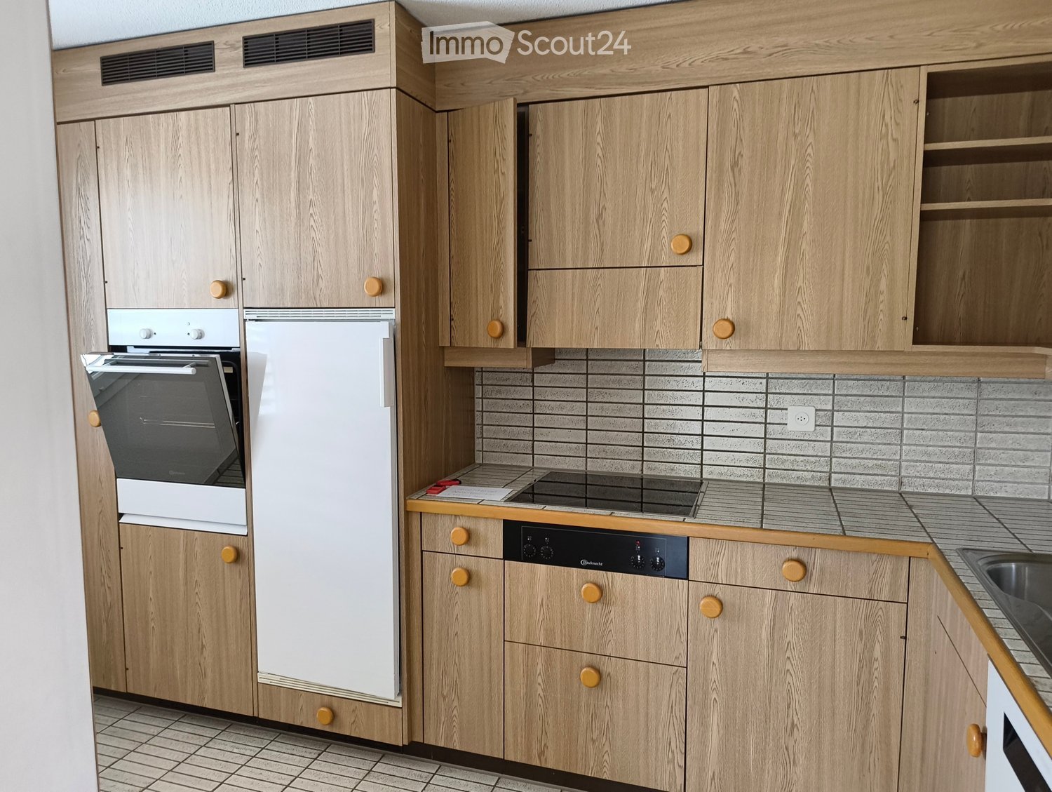 Modern kitchen with light wooden cabinets, stainless steel appliances, and tiled backsplash.