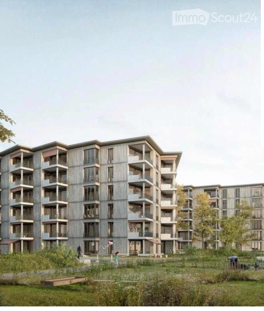 Modern multi-story residential building with balconies and large windows, surrounded by green space and trees.