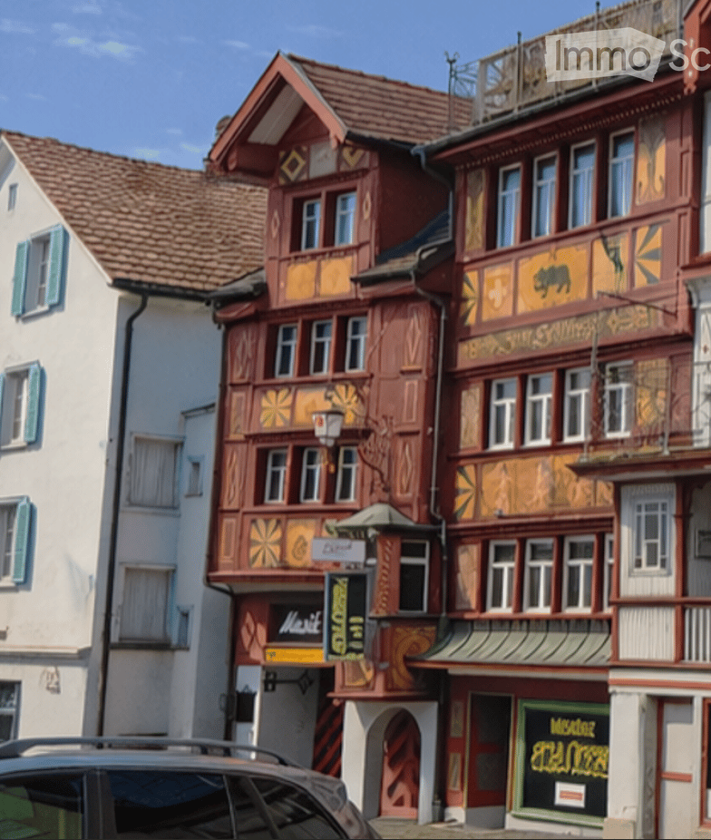 A row of traditional half-timbered houses with colorful facades, decorative carvings, and multiple stories, featuring shops and signage at the ground level.