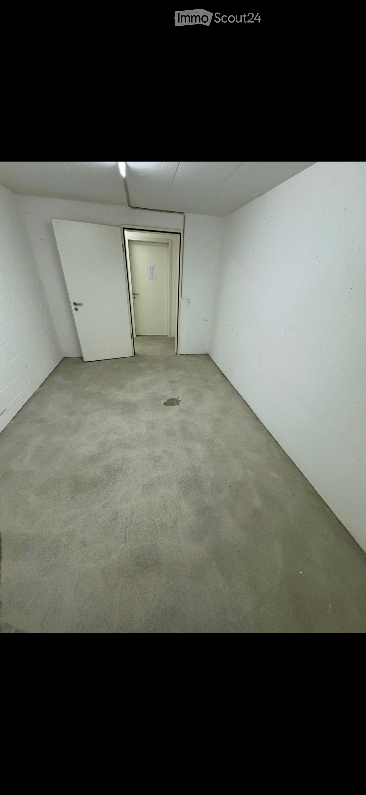 Empty room with concrete floor, white walls, and two doors.